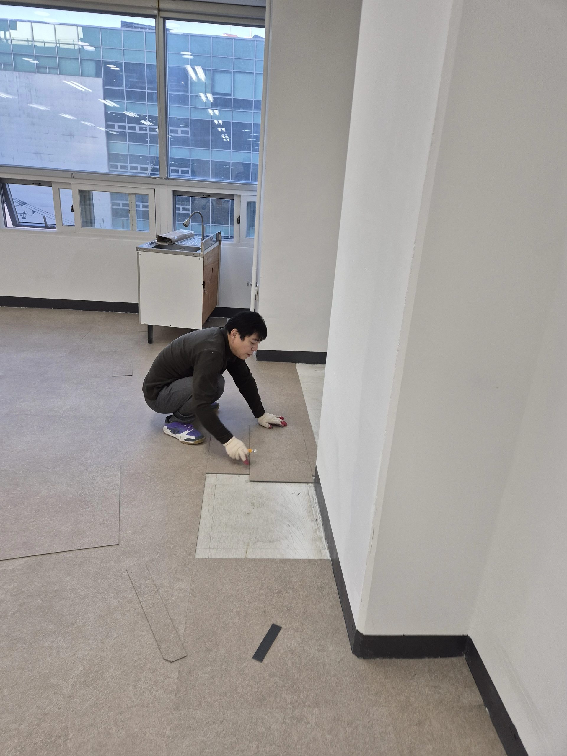 무릎을 꿇고 데코타일을 커터로 재단해 시공하는 작업자